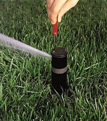 a Concord Sprinkler Repair tech adjusts a sprinkler head